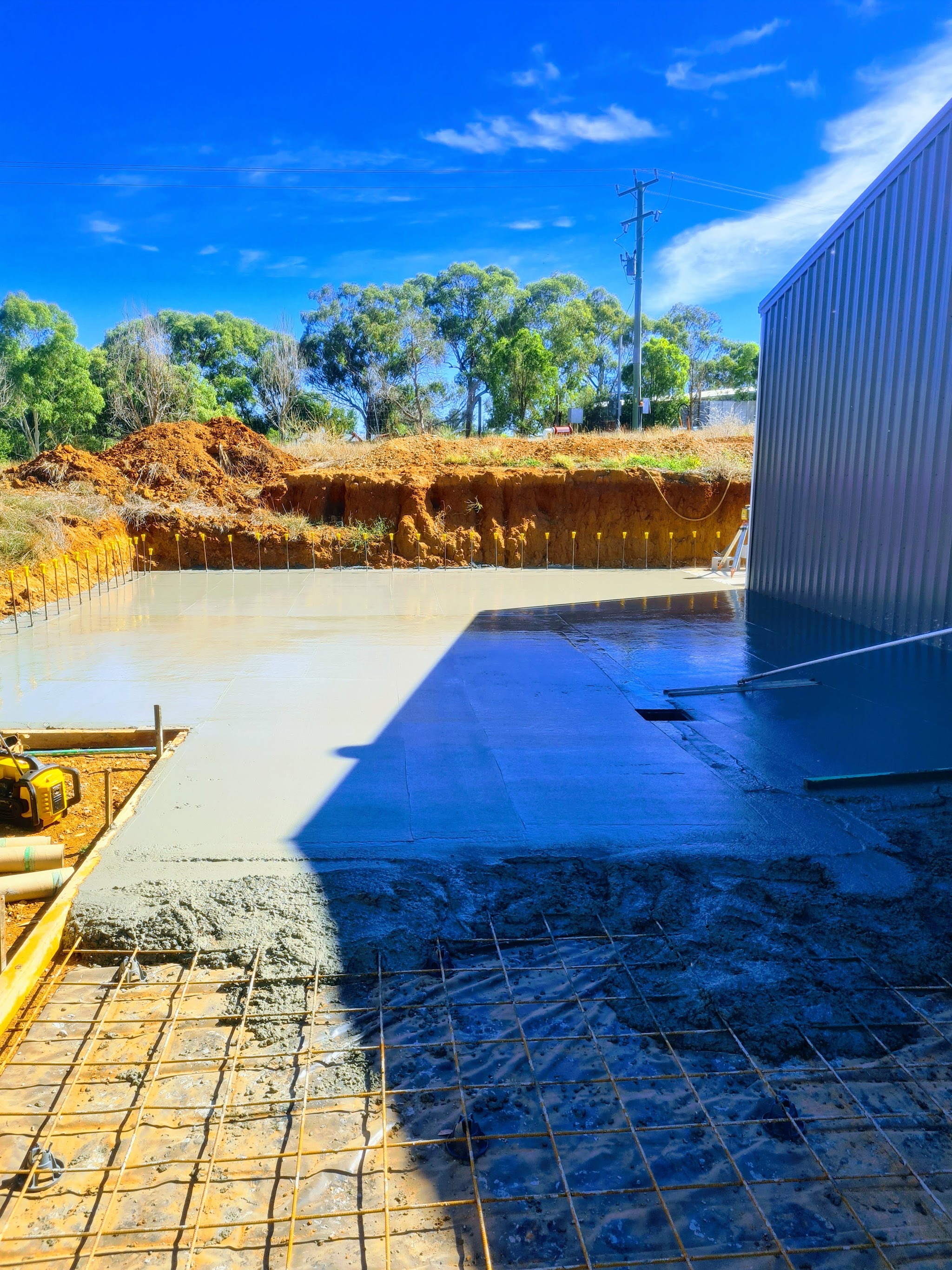 Reinforcement mesh laid out beside a shed with the pour underway