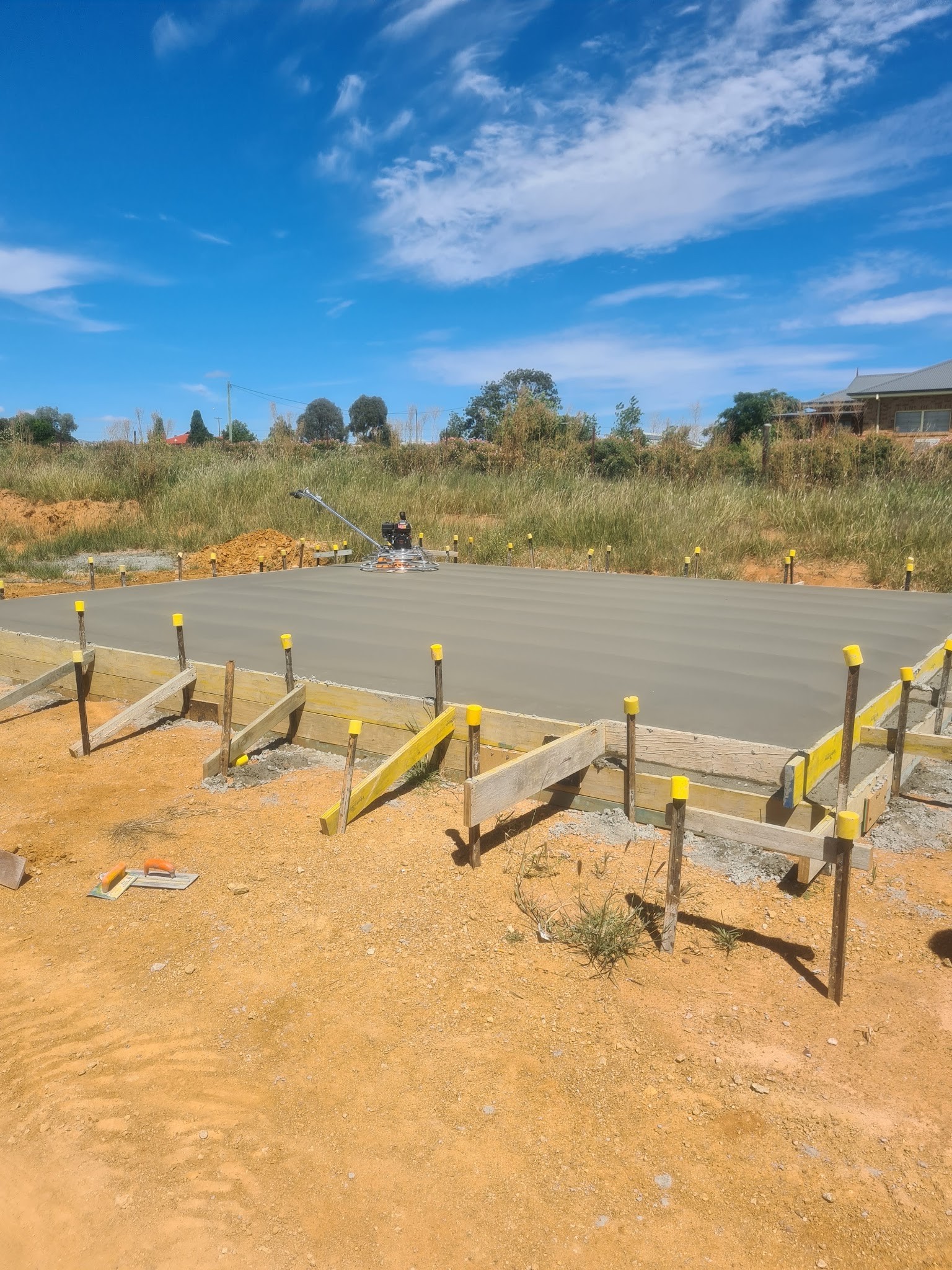 Timber formwork and stakes set out for a long slab on a rural block