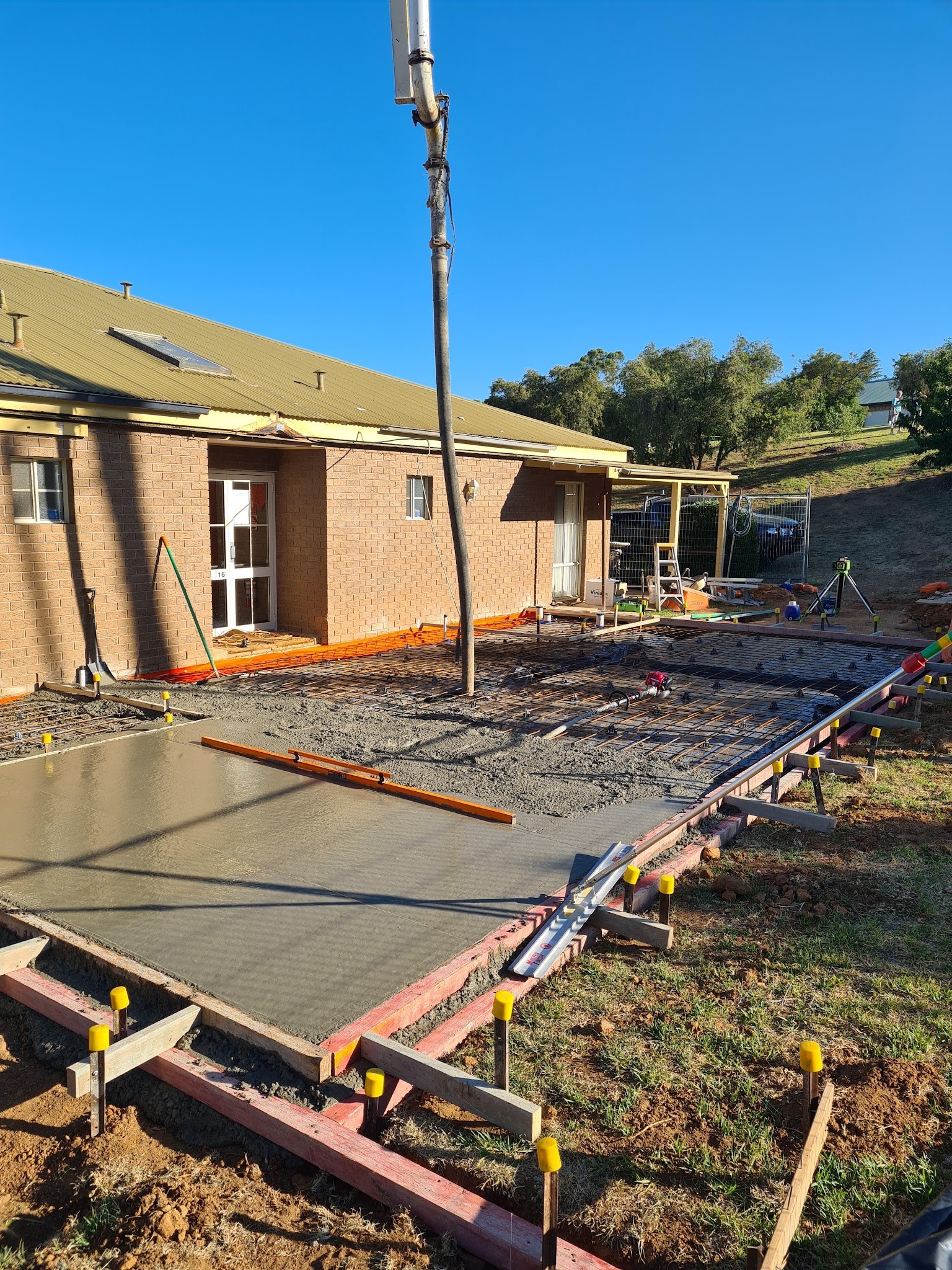 Concrete pump hose feeding a driveway pour next to a brick house