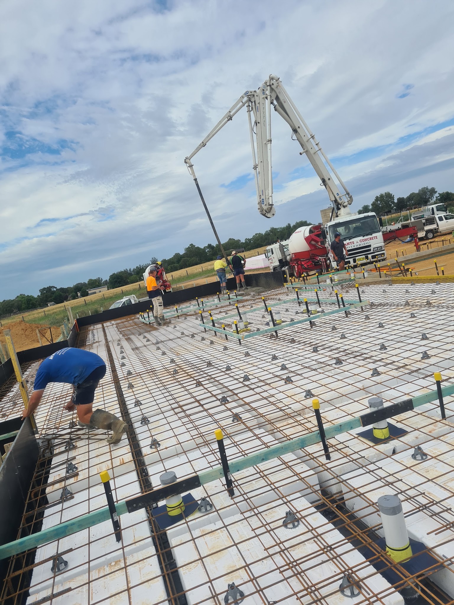 Concrete boom pump and crew working over a large reinforced slab